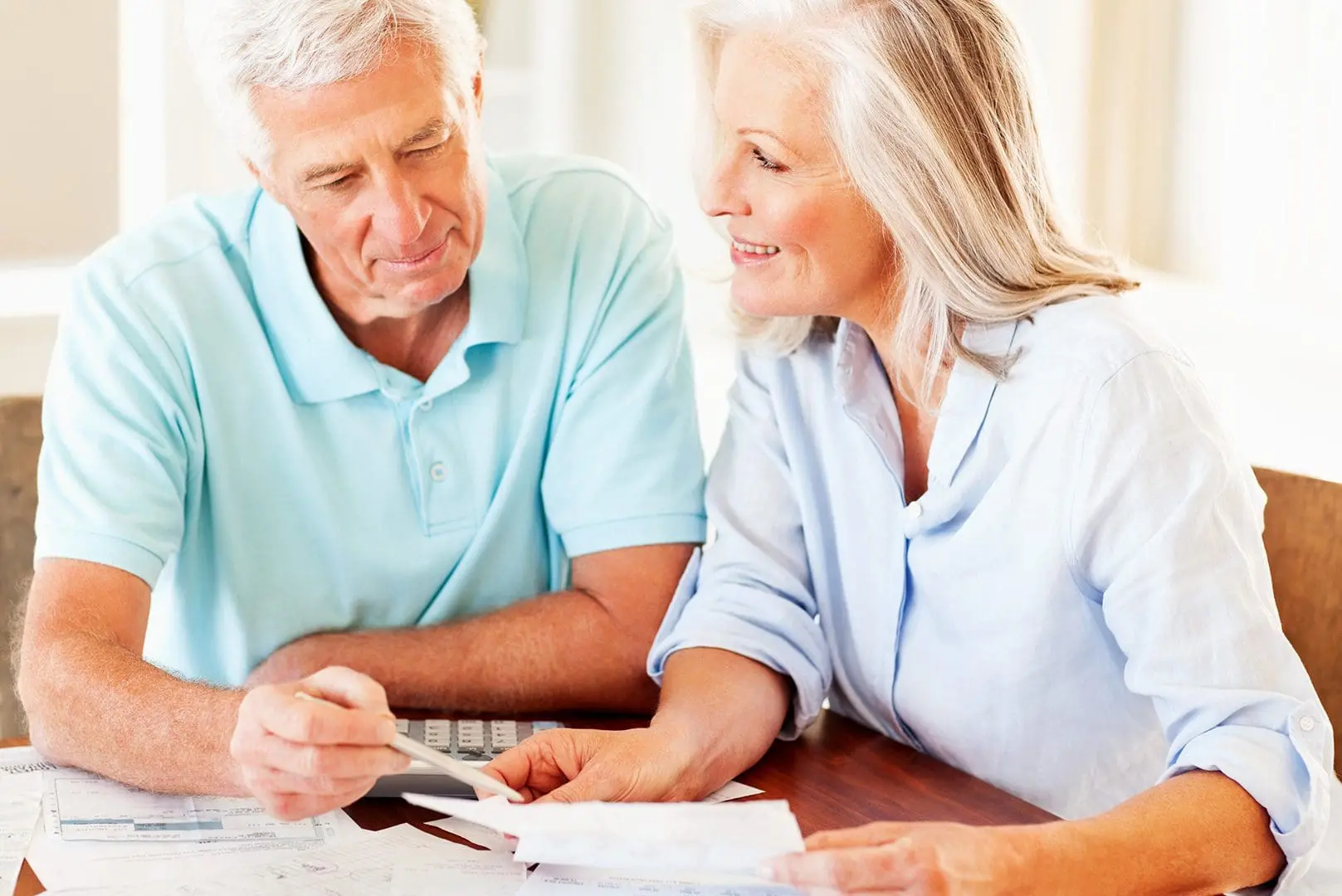 Couple Calculating Monthly Expenses senior couple reviewing their finances at the table