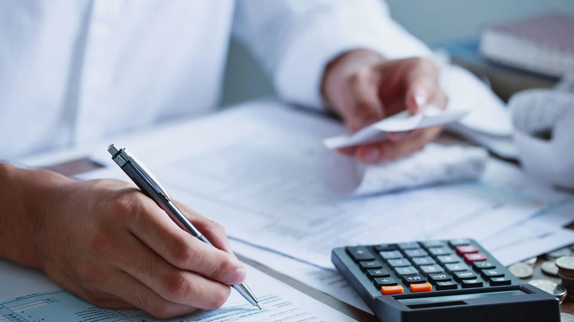 Man hand filling US tax form. tax form us business income office Financial document. Tax time.Tax concept. Close-up. Man hand filling US tax form with calculator