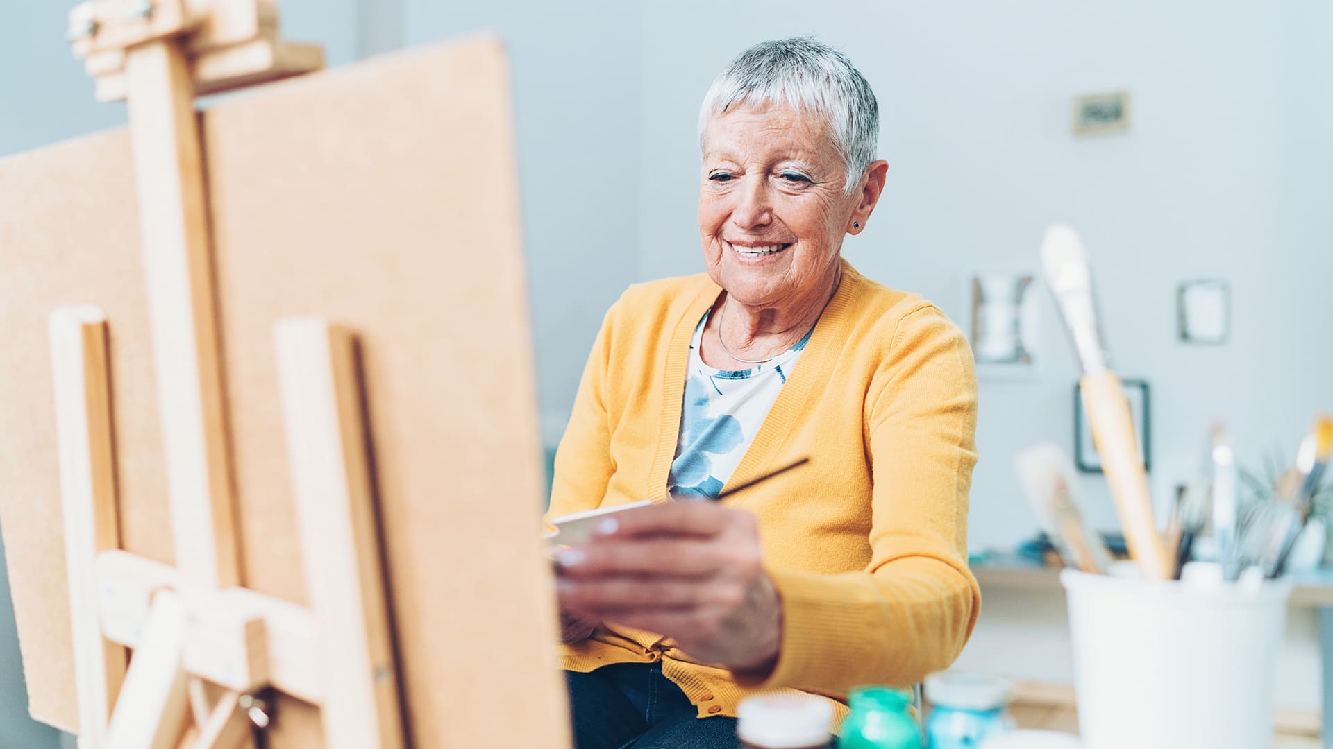 senior woman painting on an easel