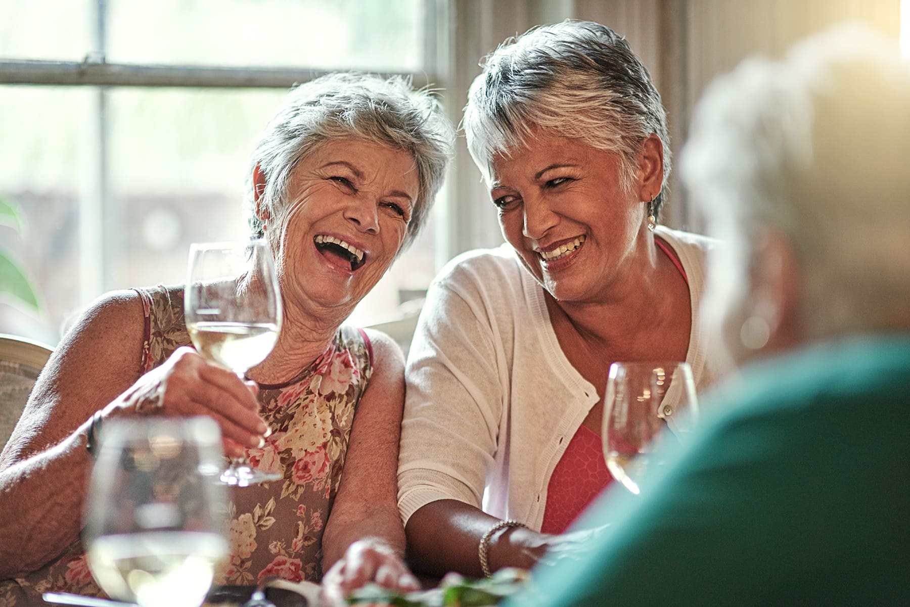 senior women laughing and smiling together at the dinner table