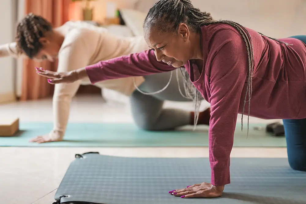 Curvy african mother and daughter doing yoga exercise together at home