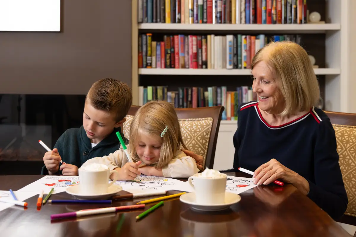 A senior woman coloring with her grandchildren at Canterbury Woods
