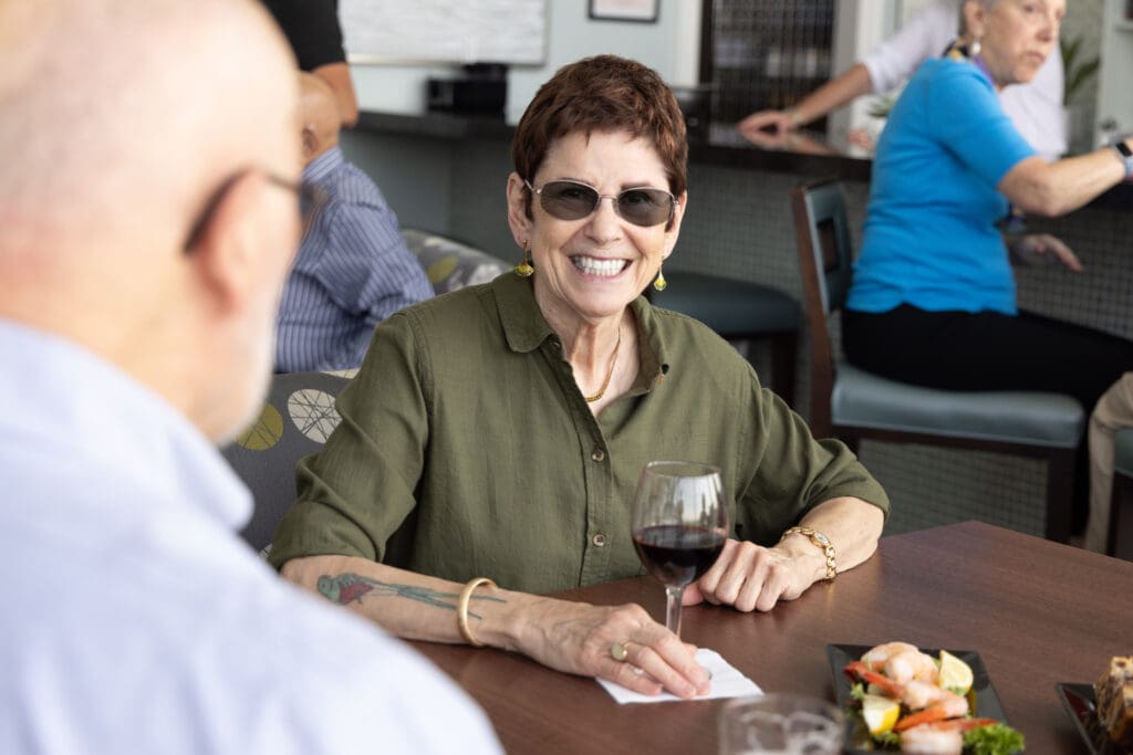 An elderly woman at Canterbury Woods Gates Circle sitting with other members of travel clubs for seniors.