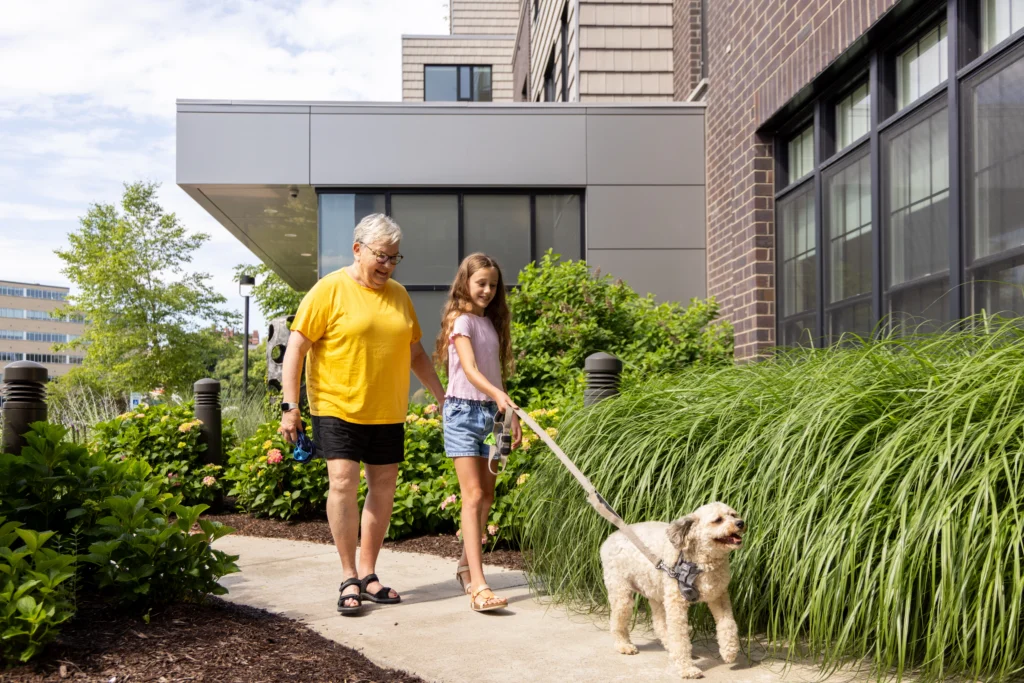 senior woman and granddaughter walking dog outside at Canterbury Woods
